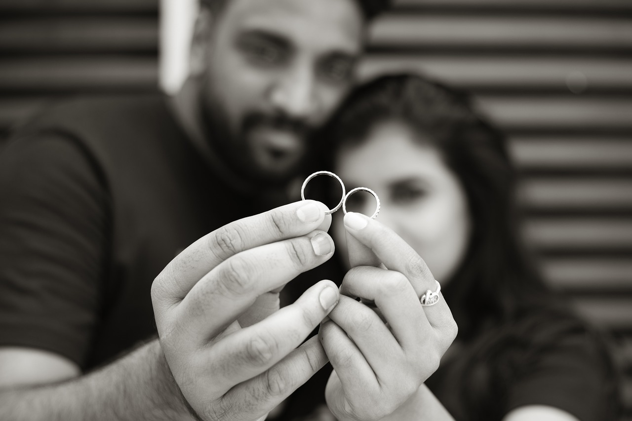 A couple holding wedding rings, representing the benefits of prenuptial agreements in Arizona.