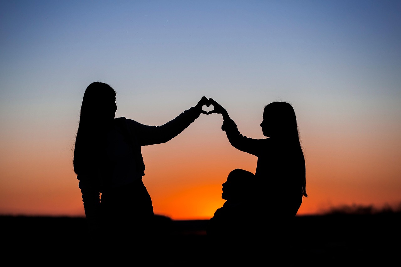 Silhouettes of a family at sunset with their hands forming a heart, representing the advantages of a boutique Phoenix family law firm.